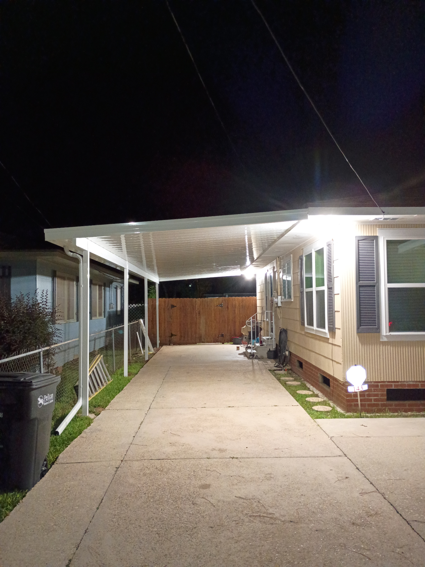 Illuminated ribbed underside of a white flat pan aluminum patio cover